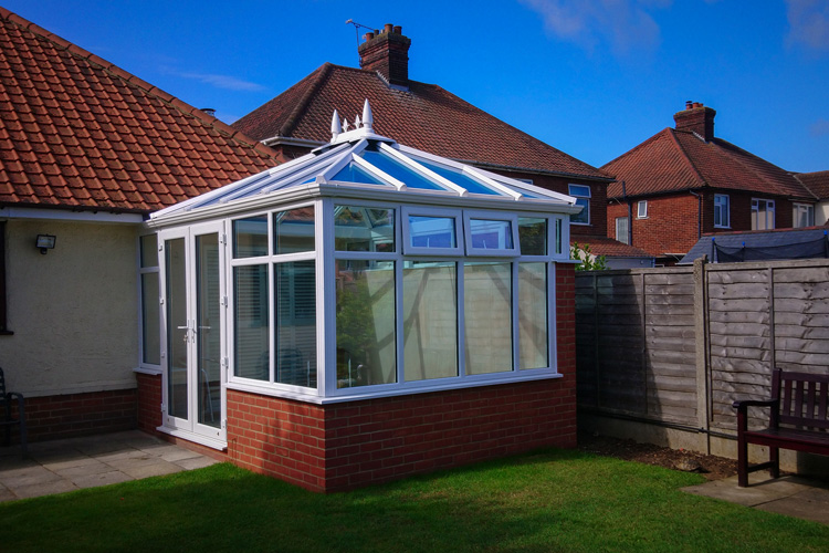 Double Hip Edwardian Dwarf Wall Conservatory, White PVCu windows & French doors. Solar control self cleaning glass roof, Box Gutter to house wall